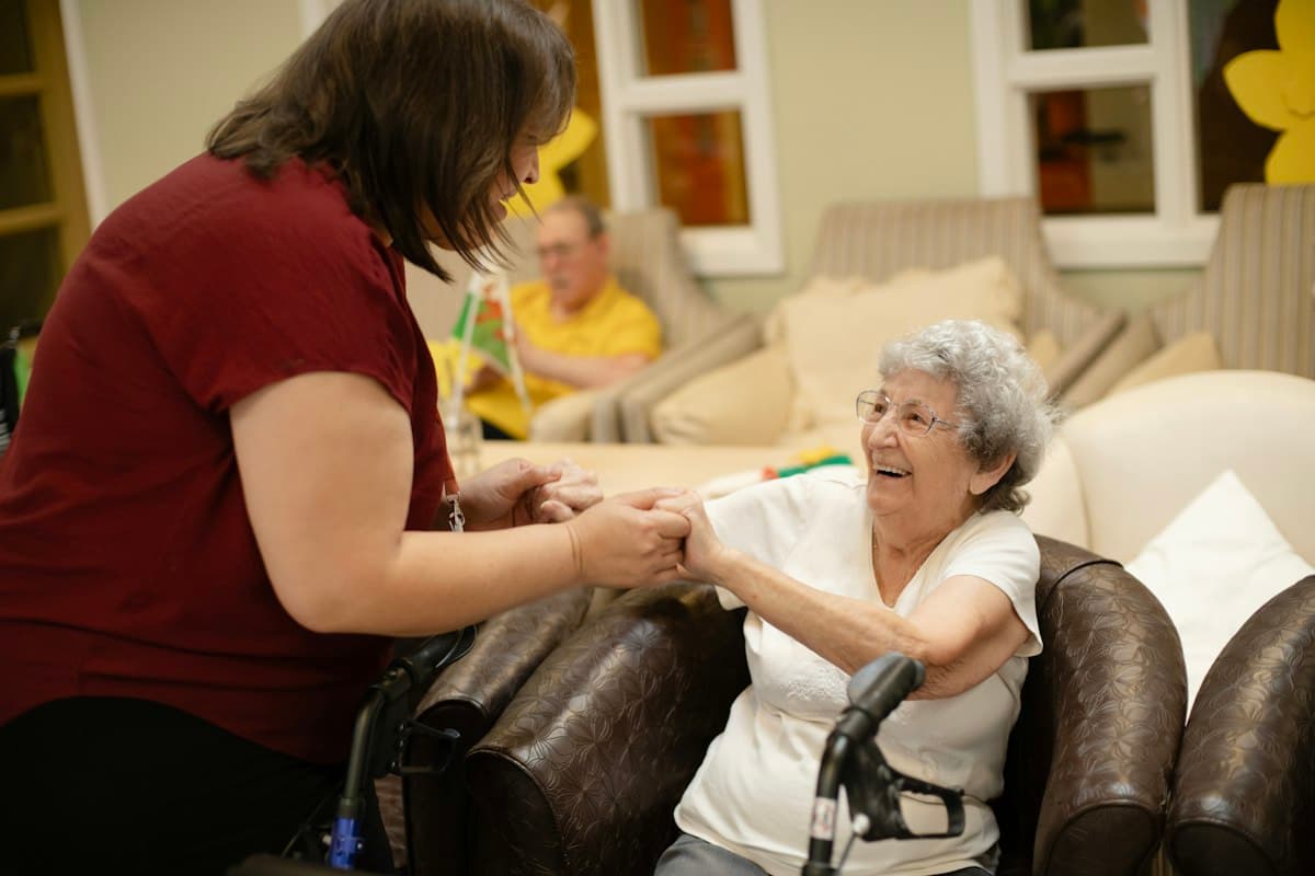 A caregiver helping an elderly woman stand with her walker